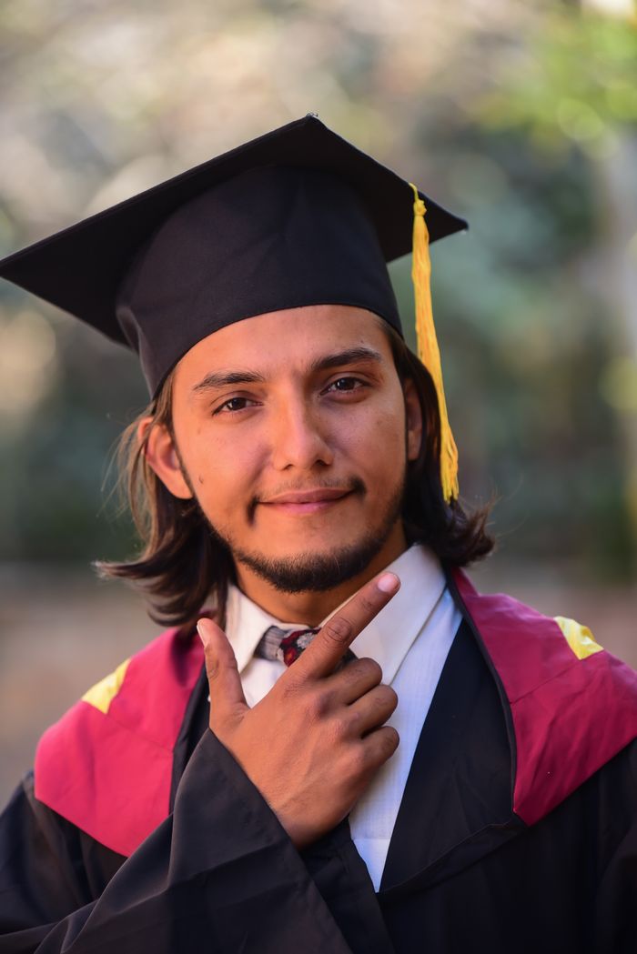 our-experience Proud graduate posing with cap and gown, symbolizing academic achievement and success.