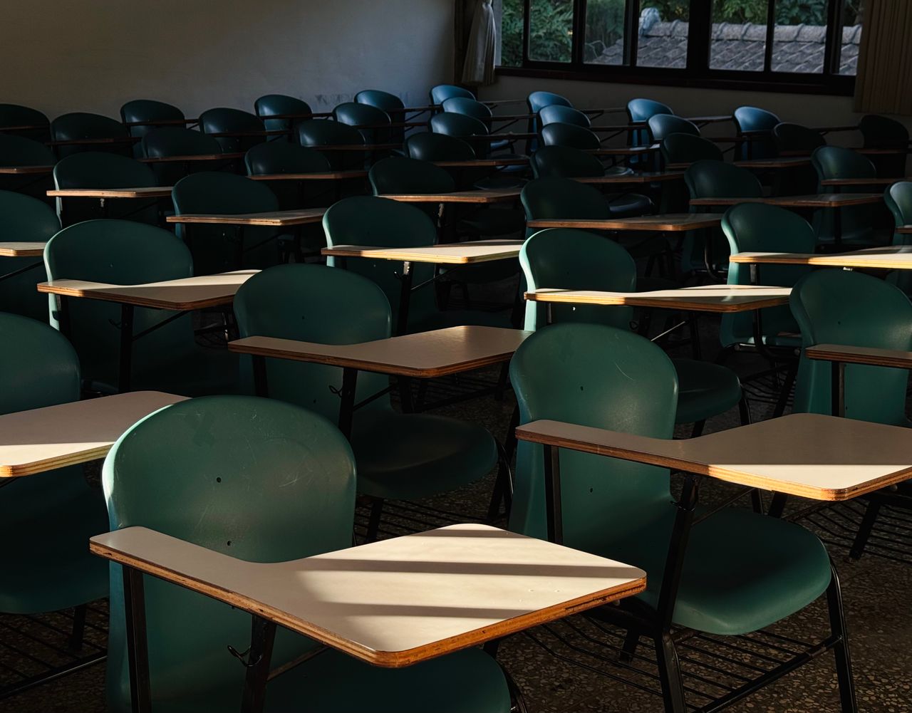 services-03 An empty classroom with sunlit desks, evoking a quiet and serene atmosphere.