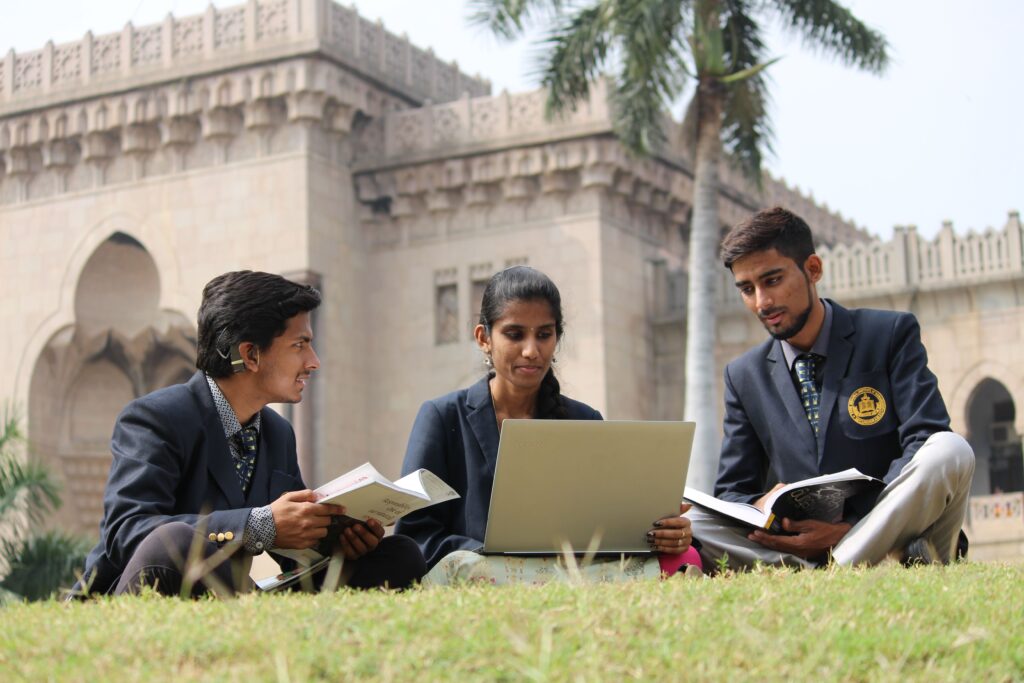 pexels photo 4622108 4622108 Ground level of young ethnic students in uniform sharing laptop and books while preparing for exam in yard of university