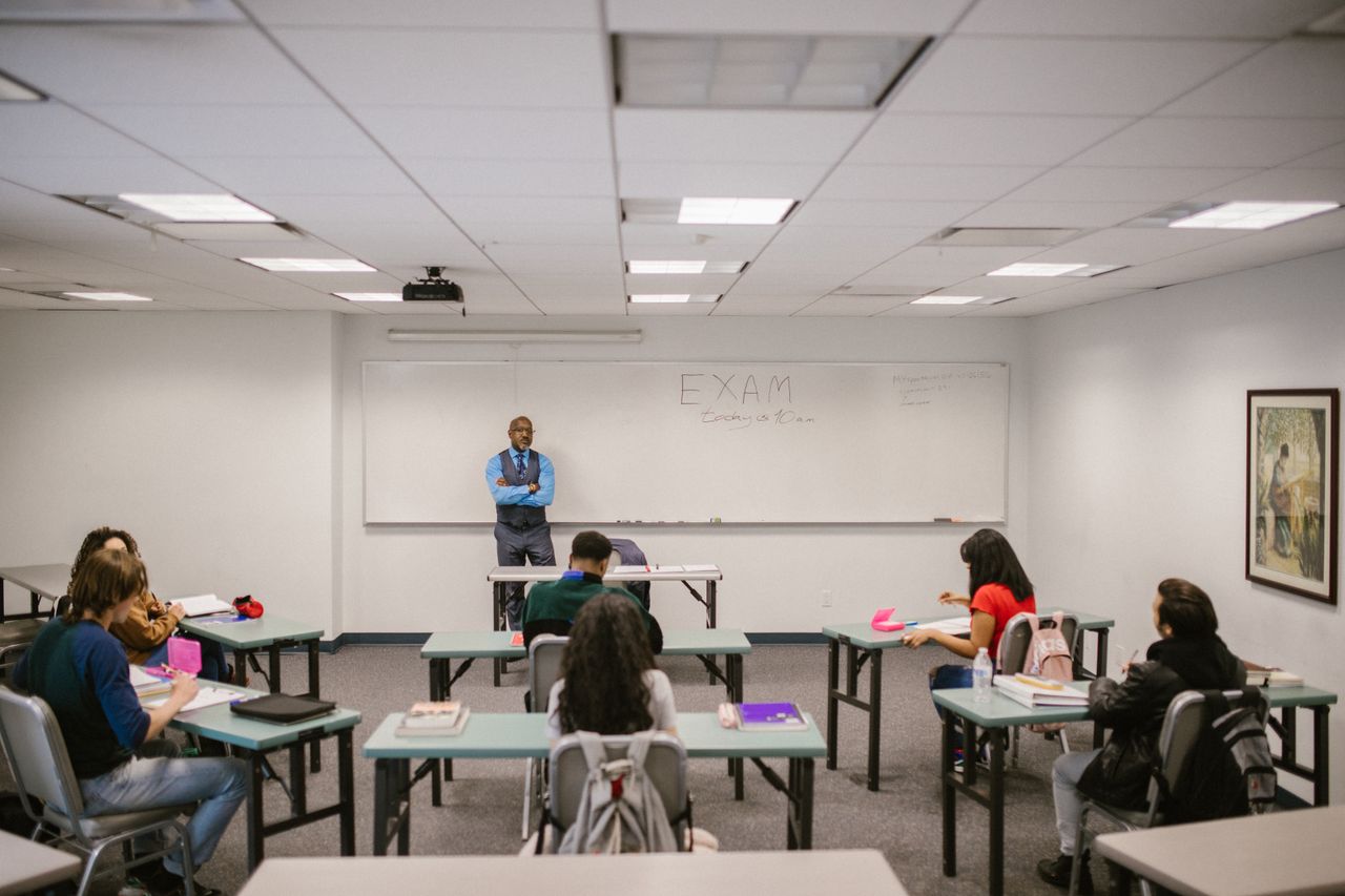 The Art of Drawing Readers In: Your attractive post title goes here A classroom setting with a teacher proctoring an exam, students focused on their tests.